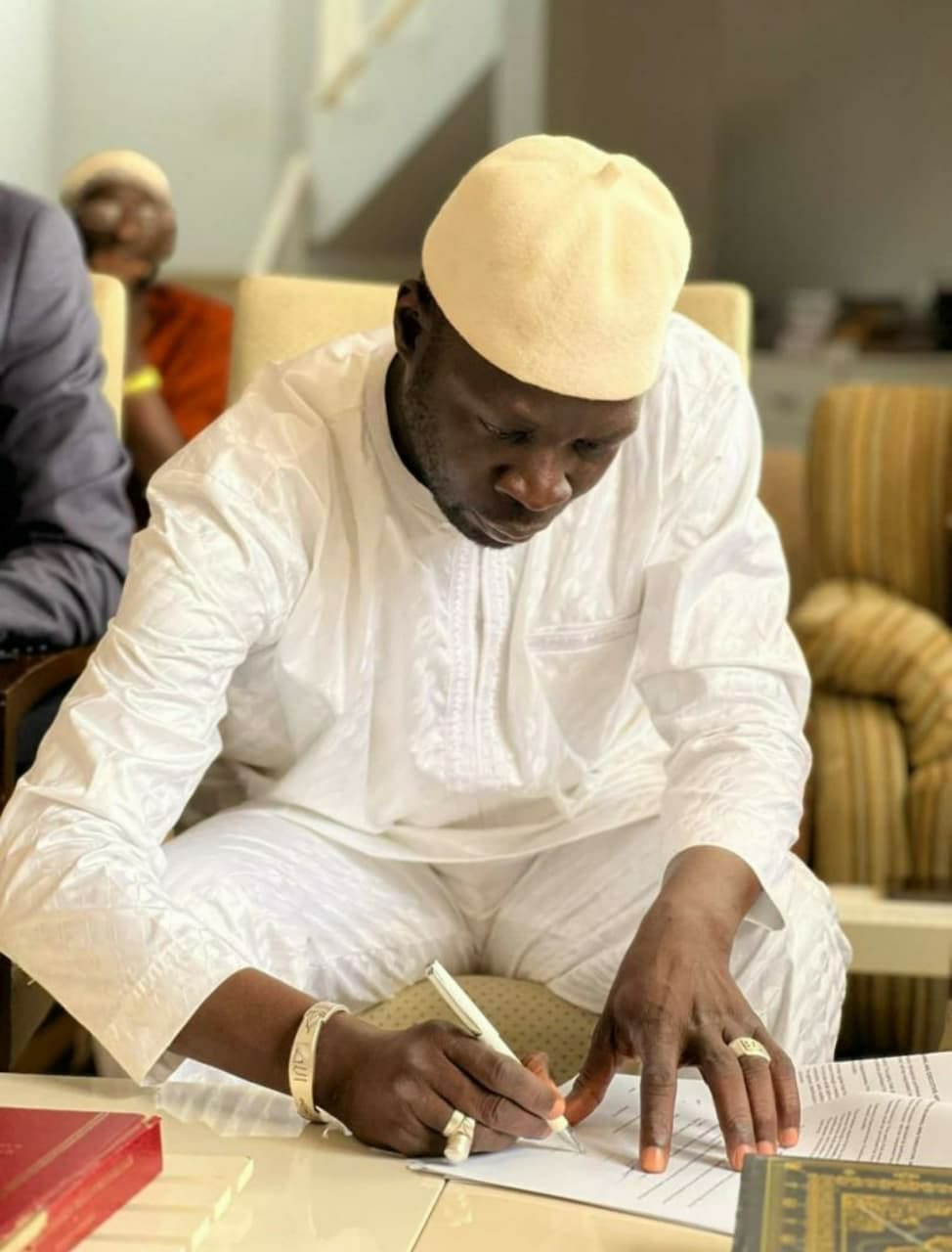 Kebba Madi Bojang signing a document